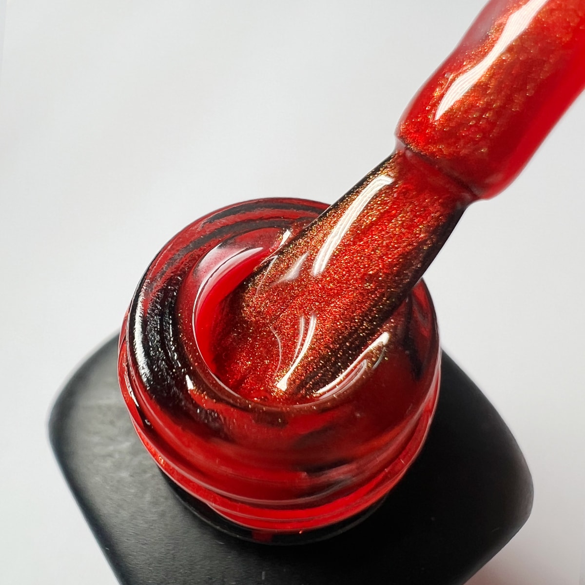 Pennello dello smalto rosso Chili Pepper estratto dal flacone, mostra la consistenza del colore shimmer.