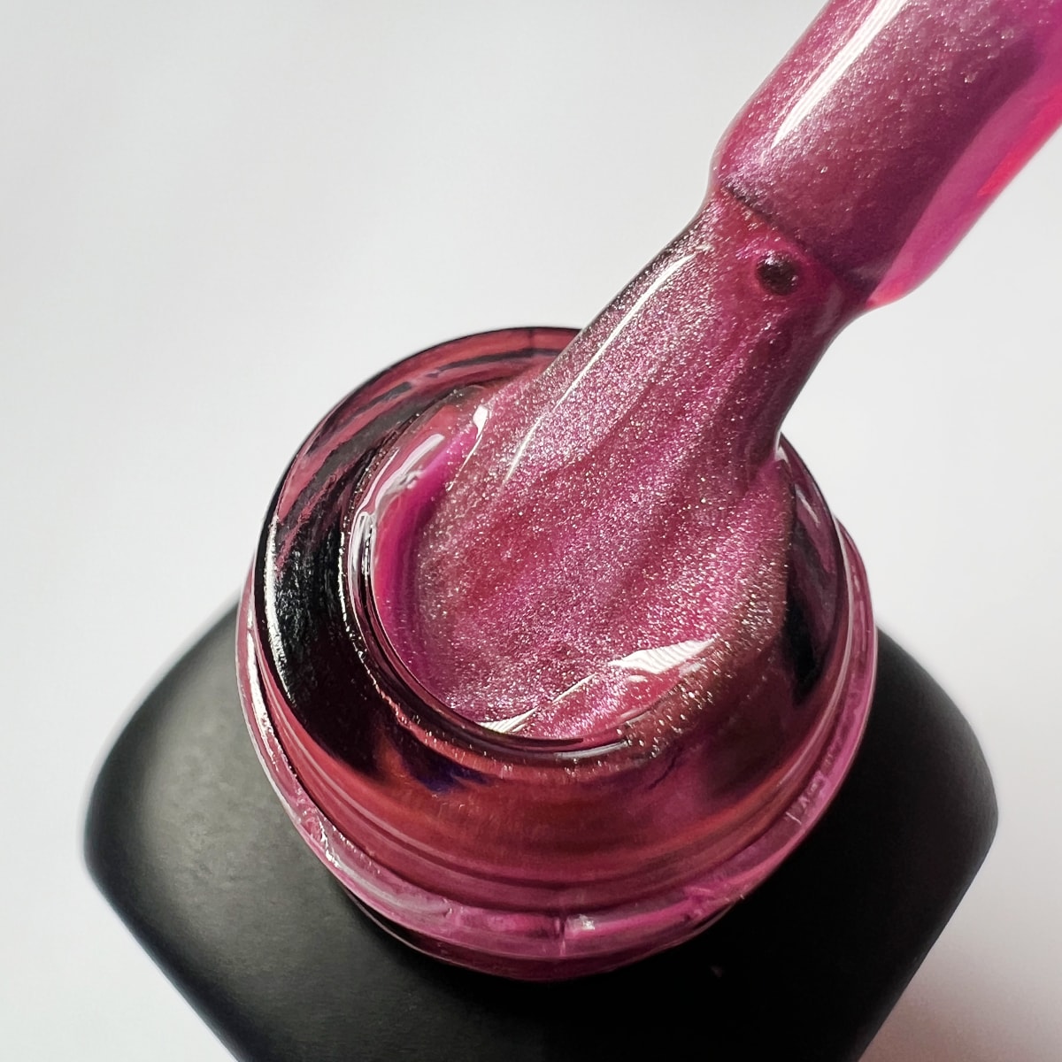 Pennello intinto nello smalto peel-off fucsia glitterato Baby Pink, texture cremosa con micro-brillantini
