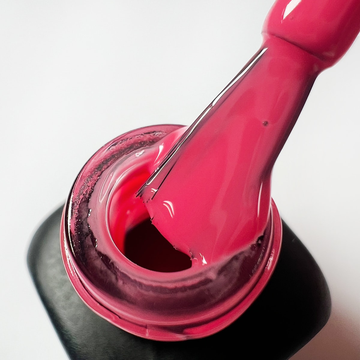 Pennello intinto nello smalto peel-off rosa fucsia Guava, texture liscia e uniforme