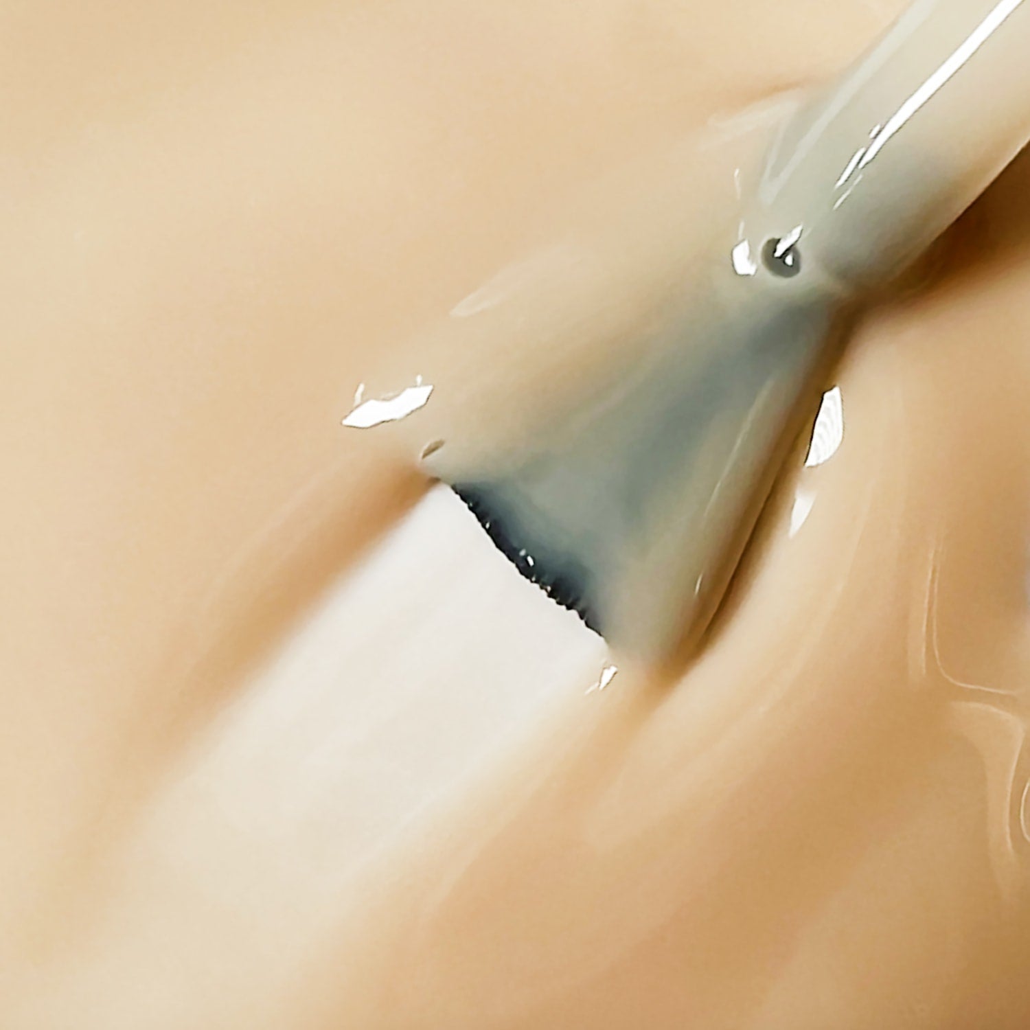 Primo piano texture smalto peel-off nude beige Pale Banana con pennello, finish cremoso lucido